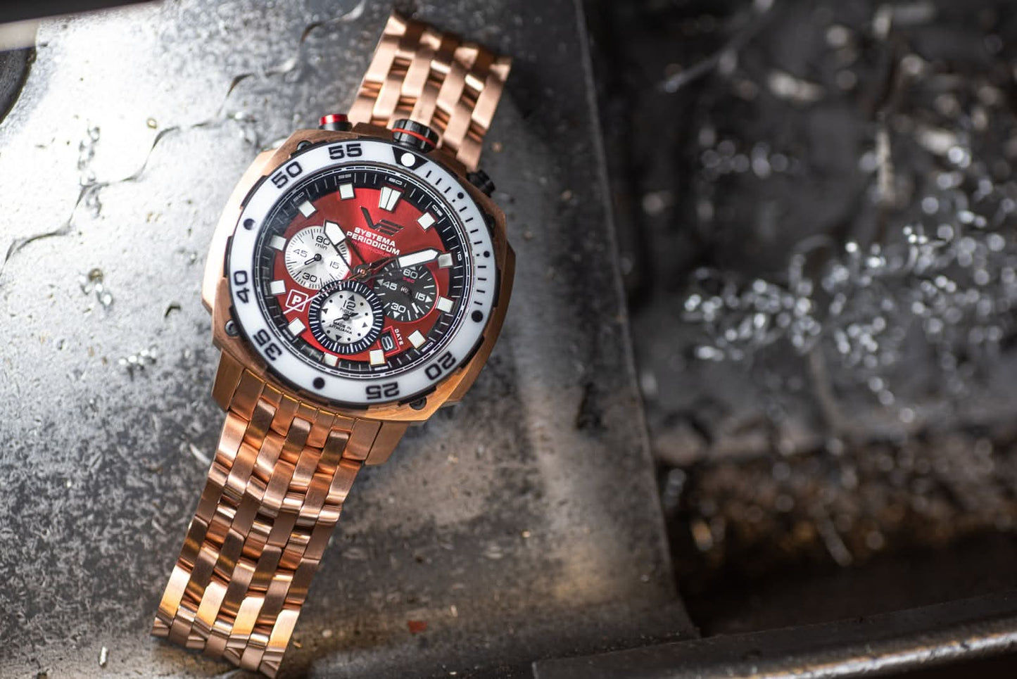 Herrarmbandsur med roséguldigt metallarmband och röd urtavla, sned vy