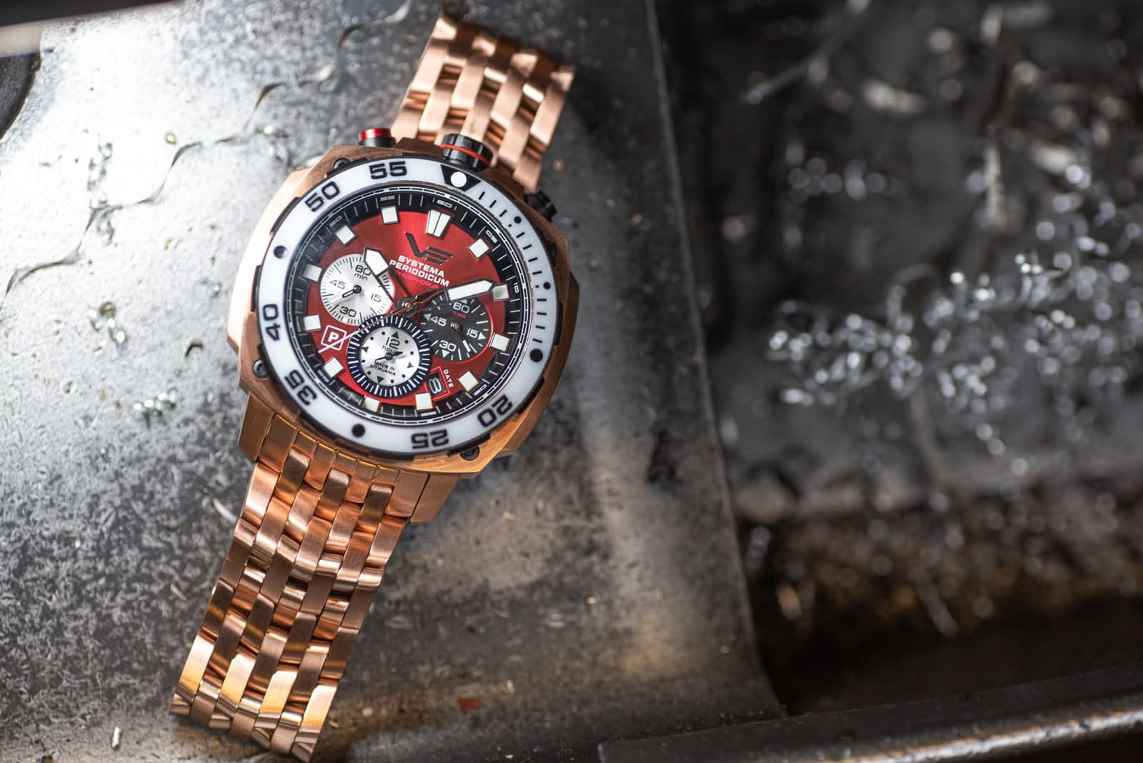Herrarmbandsur med roséguldigt metallarmband och röd urtavla, sned vy