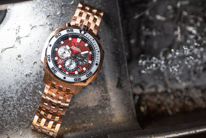 Herrarmbandsur med roséguldigt metallarmband och röd urtavla, sned vy