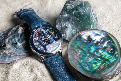 Damklocka med blått armband och runt boett; urtavla i abalone med indexmarkeringar