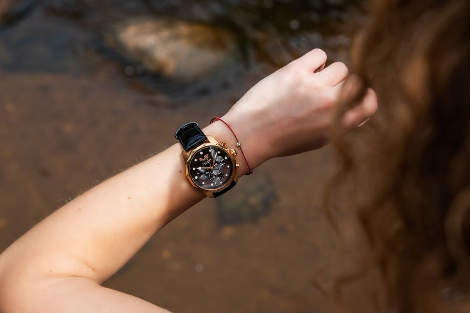 "Damenuhr am Handgelenk: svart urtavla med roséguldpläterad ram och läderarmband"