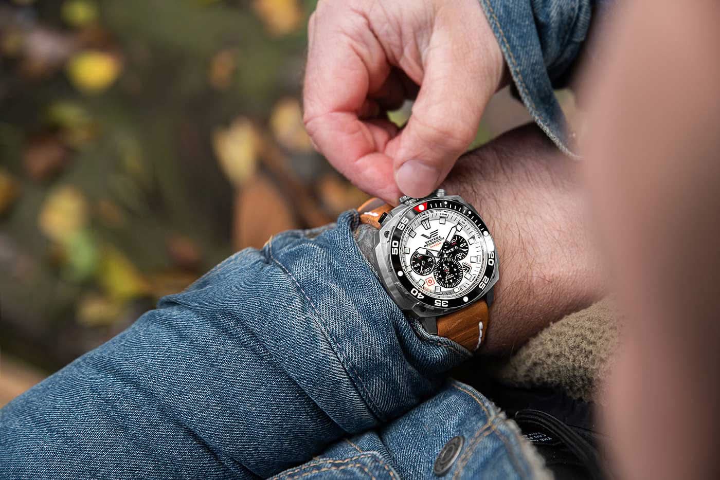 Herrklocka på handleden med brunt läderarmband och silverfärgat hölje, svart infattning