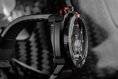 Herrarmbandsur i sidoprofil: svart boett, krona med röd accent, svart armband