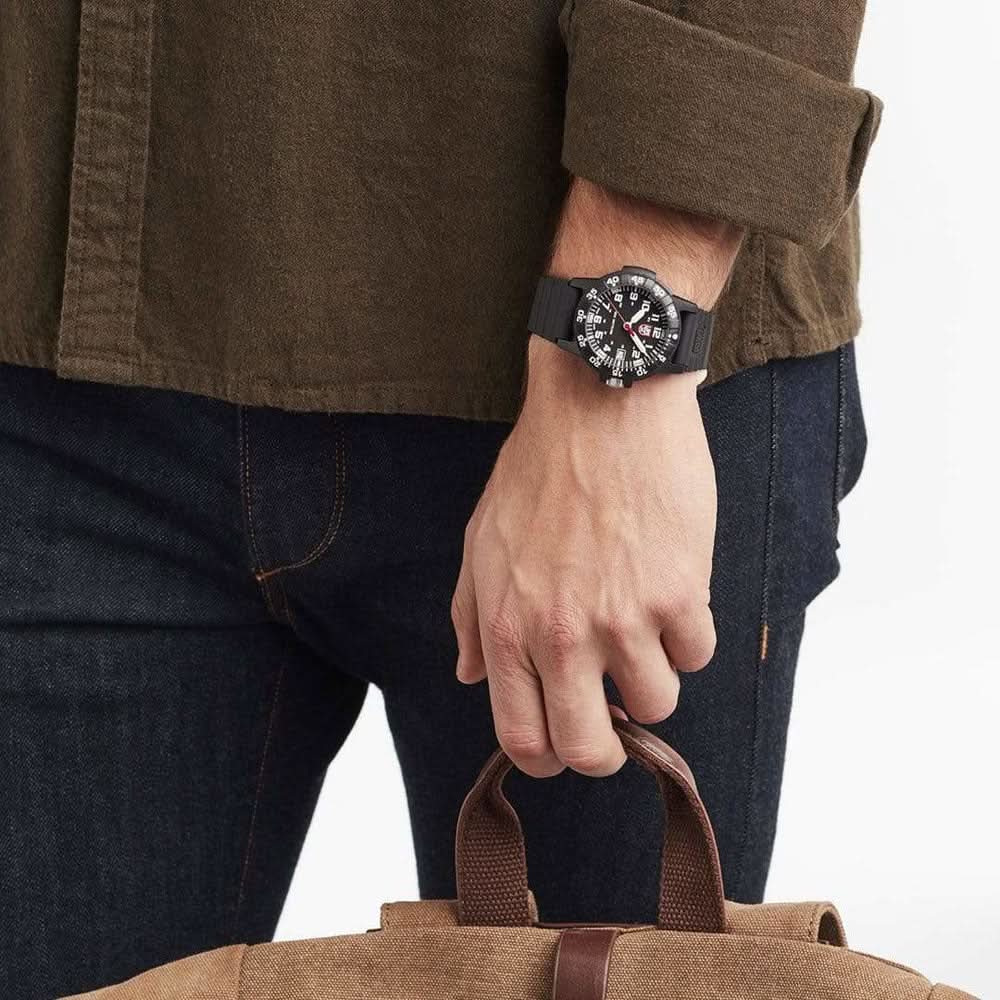 Herrklocka på handleden med svart armband och mörk urtavla