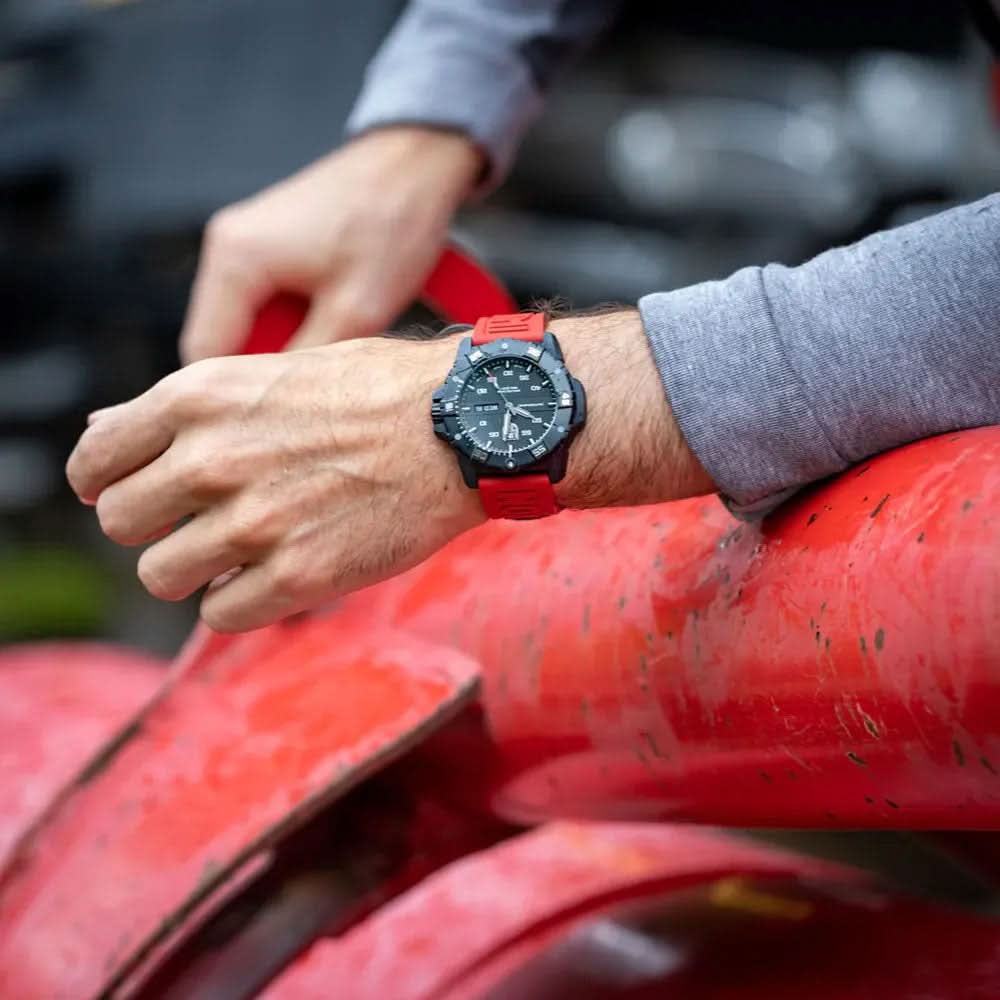 Produktbild: Automatisk klocka på handleden med rött silikonarmband mot ett rött föremål