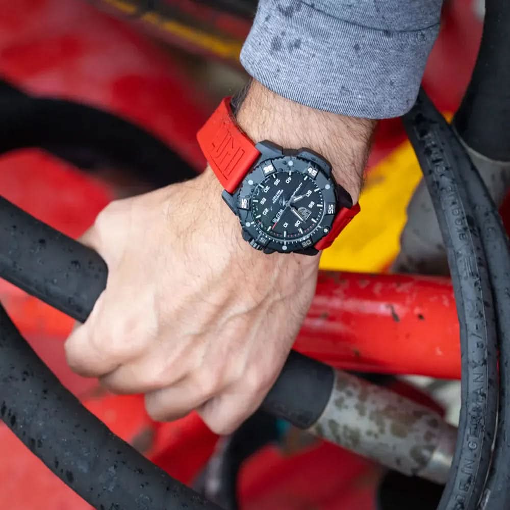 Bärbild: Automatisk klocka med rött silikonarmband på handleden mot ett gult-rött objekt