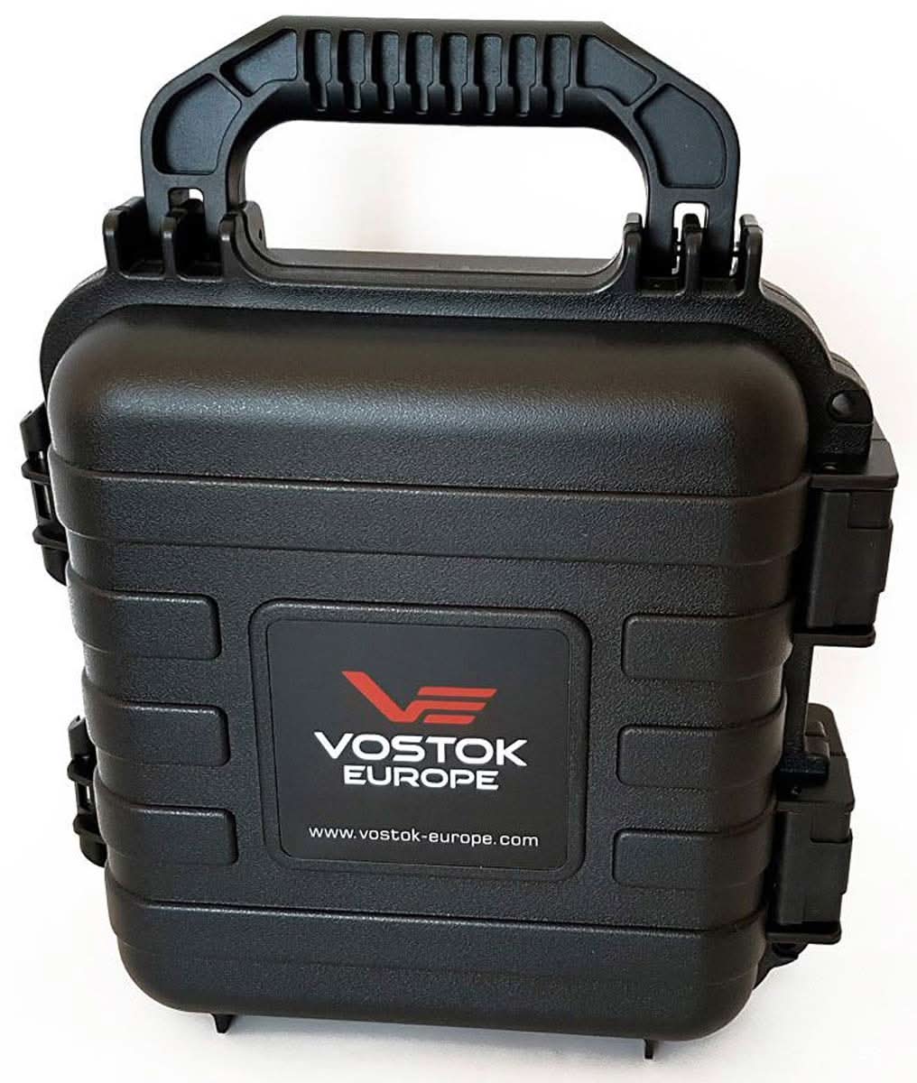Uhrenskyddslåda i svart plast med bärhandtag och Vostok Europe-logotyp