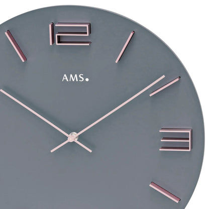 Zbliżenie na zegar ścienny: szara tarcza z różowozłotymi indeksami godzin i wskazówkami