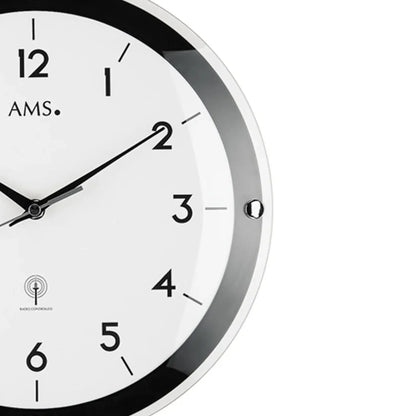 Detail der Wanduhr: silberner Rand, schwarzer Ring, Ziffern 2–4 und Zeiger sichtbar