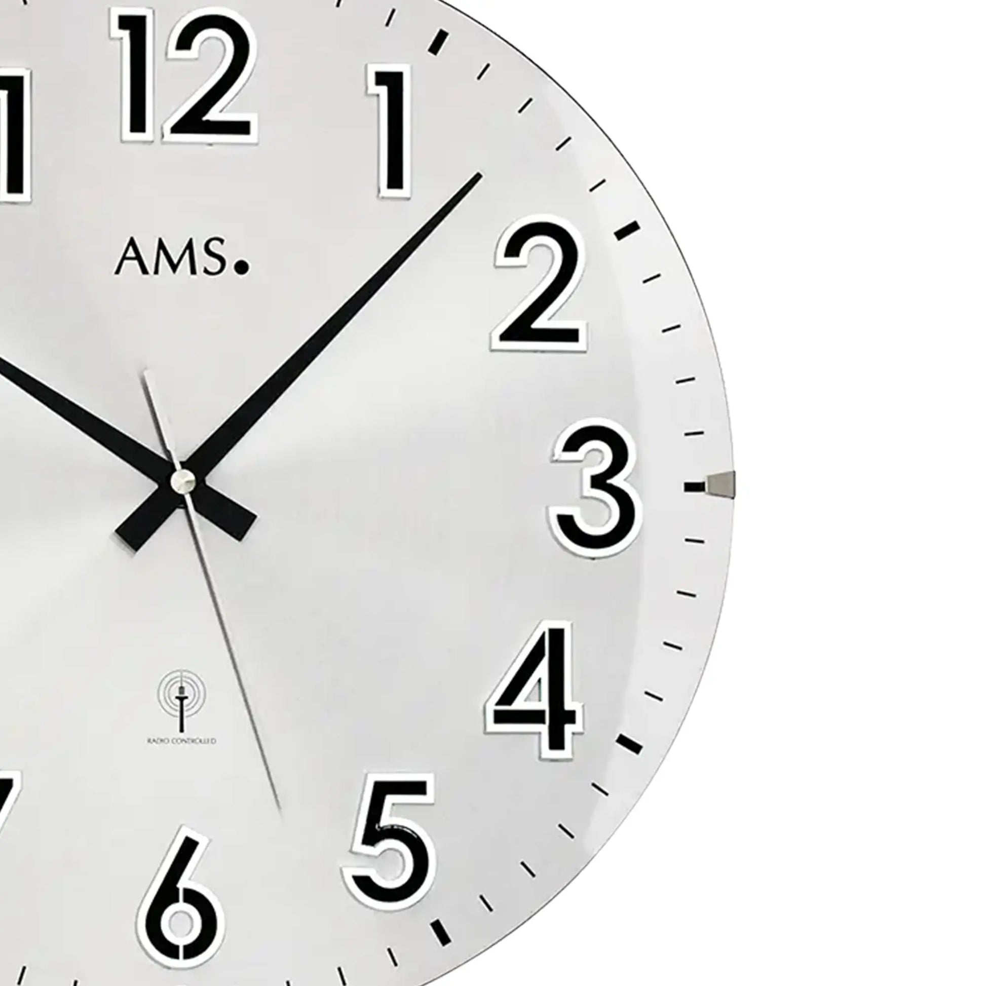 Detail der silbernen Wanduhr: weißes Zifferblatt, schwarze Zeiger, Zahlen 1–6, AMS