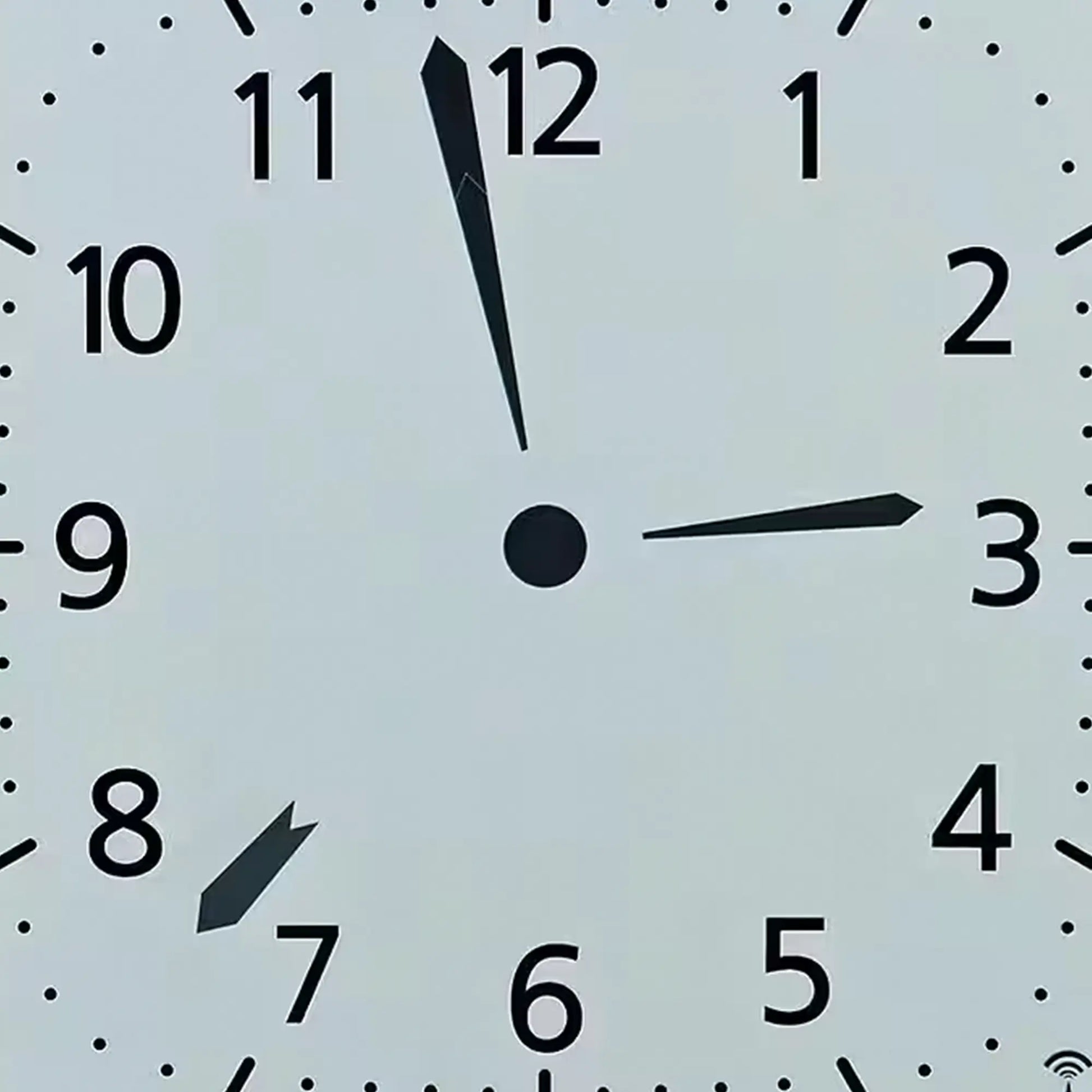 Silberne Funk-Wanduhr: Nahaufnahme des analogen Zifferblatts mit schwarzen Zeigern