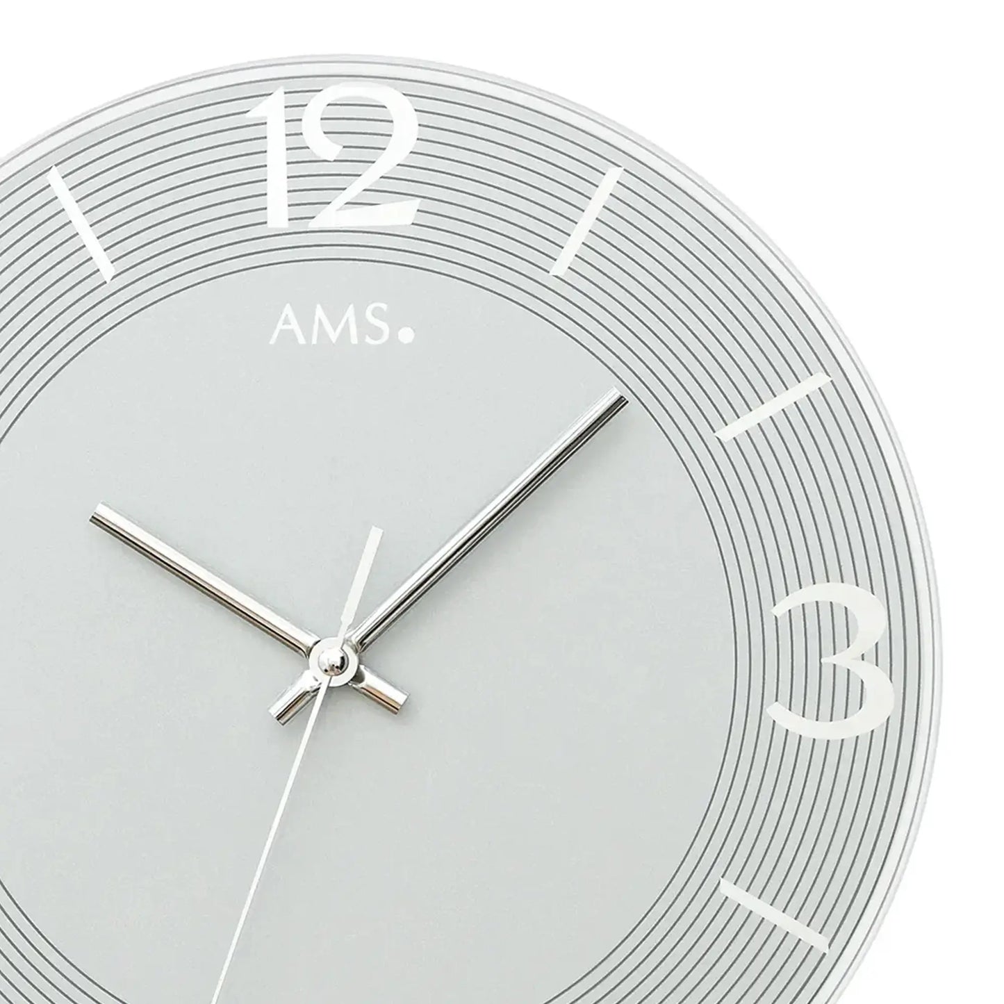 Nahaufnahme der blaugrauen AMS-Wanduhr: römische Ziffern, schmale Zeiger, feine Zeitmarken.