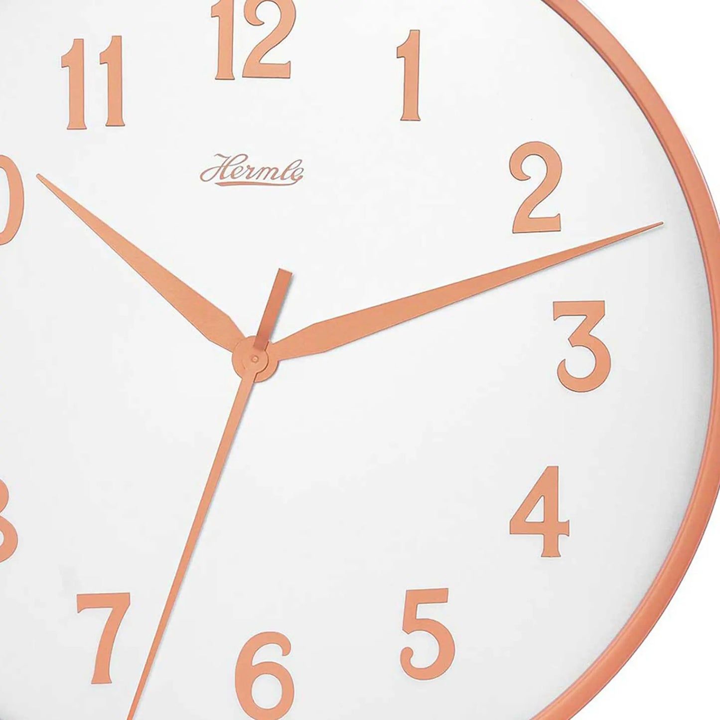 Detaljerad vy av väggklockan: vit urtavla med orange siffror, visare och Hermle-logotyp