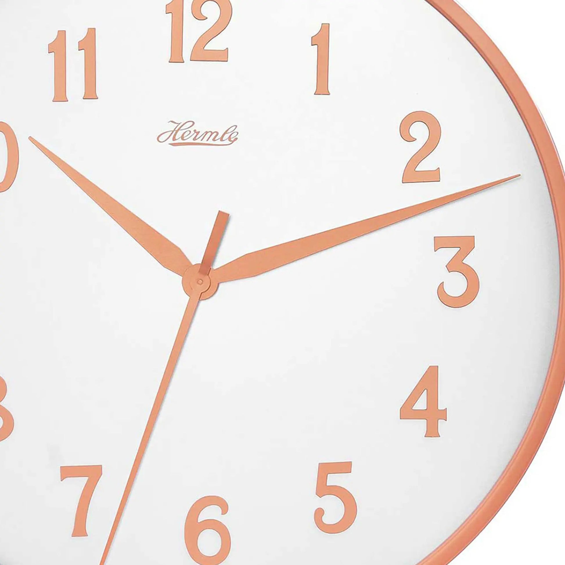 Detaljerad vy av väggklockan: vit urtavla med orange siffror, visare och Hermle-logotyp