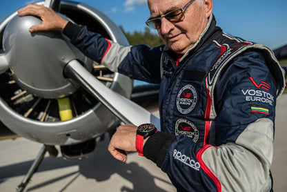 Zegarek Vostok Europe na nadgarstku z czerwonym silikonowym paskiem i czarną kopertą.