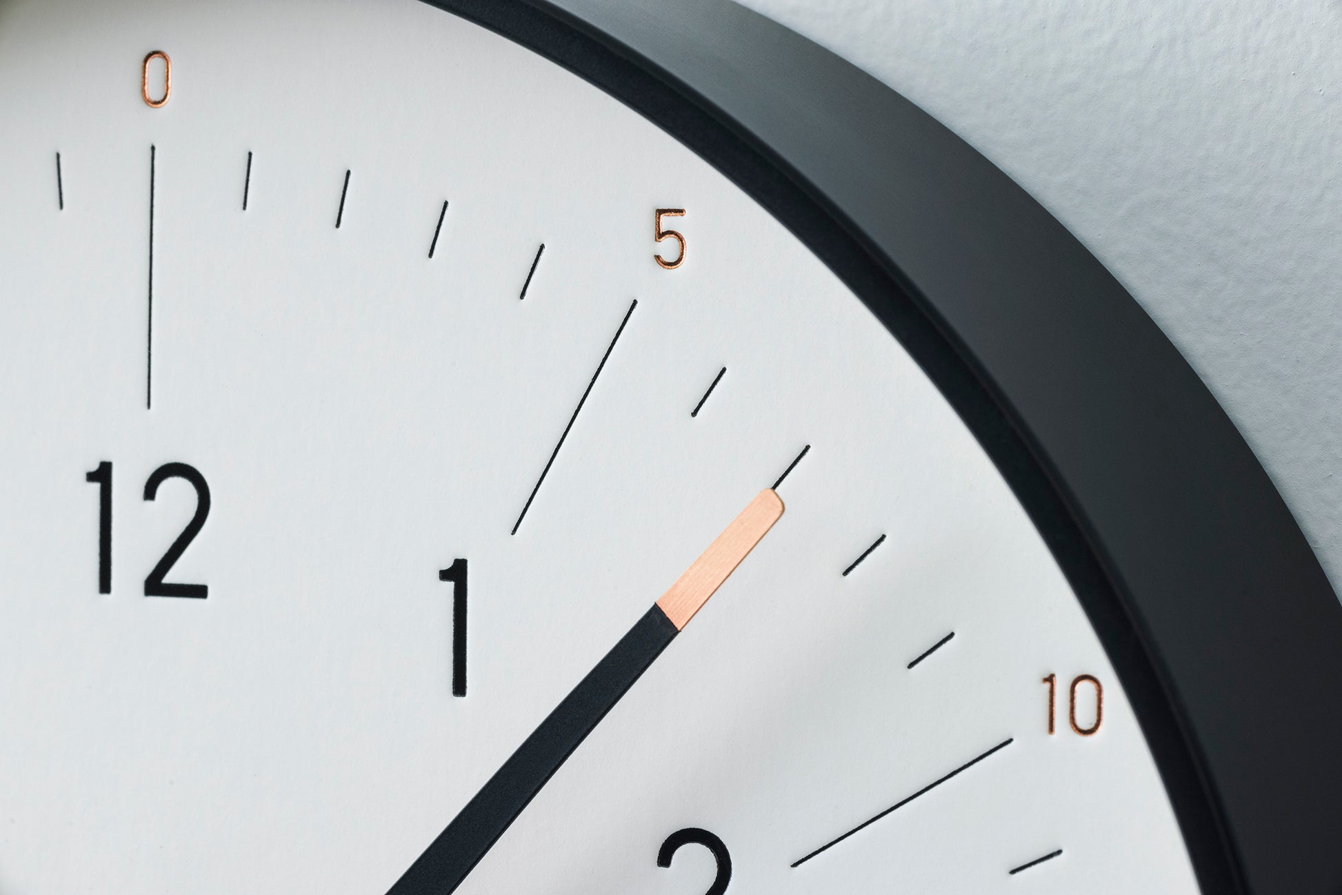 Detail vom weißen Zifferblatt der Wanduhr: schwarze Einfassung, Stundenzeiger.
