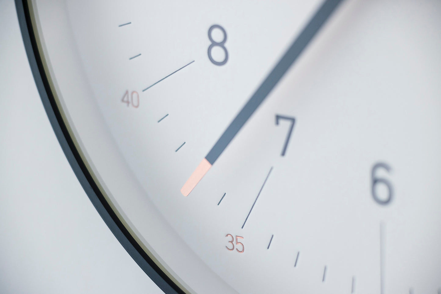 Nahaufnahme der weißen Wanduhr mit schwarzem Rand: Ziffern und feiner Zeiger.