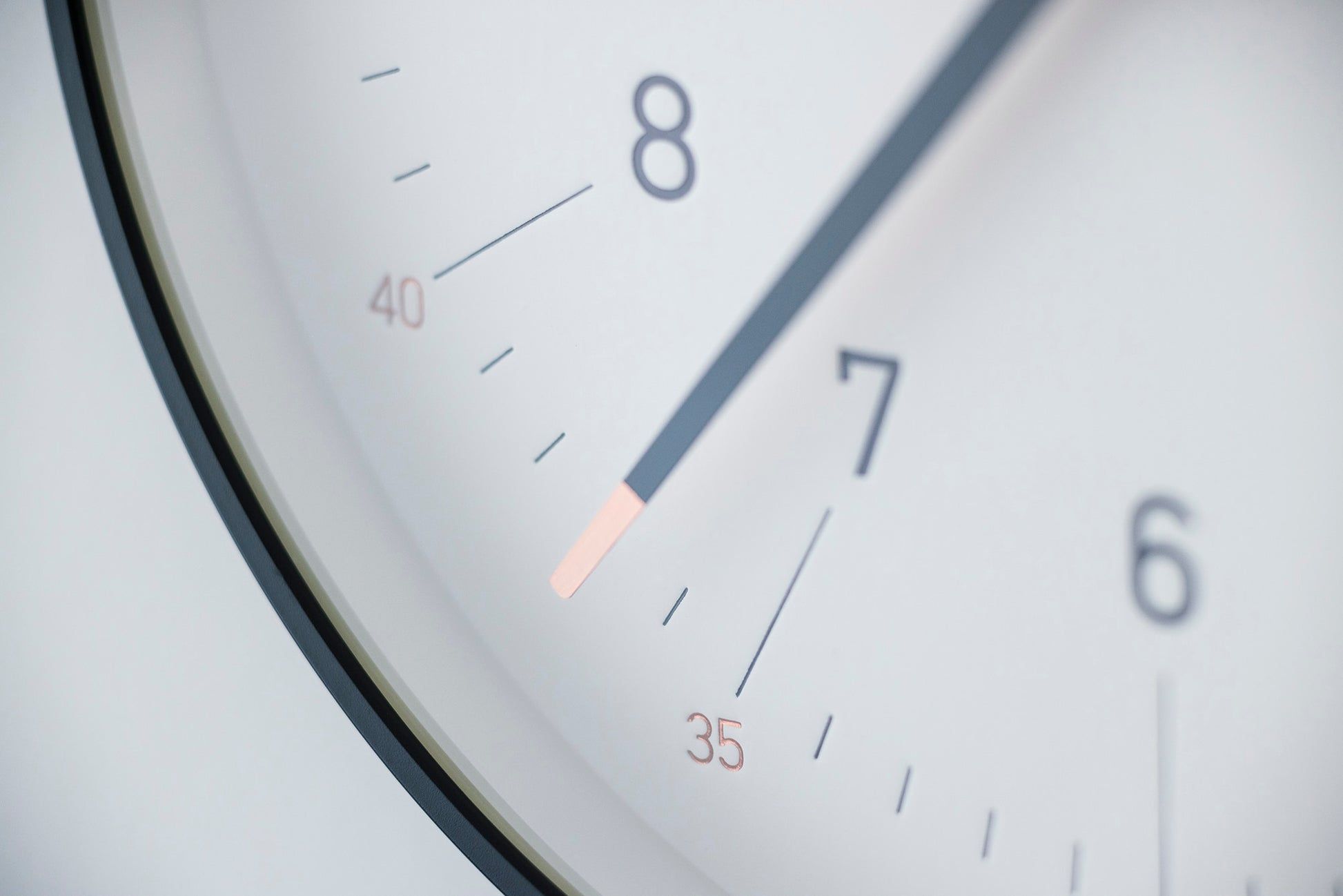 Nahaufnahme der weißen Wanduhr mit schwarzem Rand: Ziffern und feiner Zeiger.