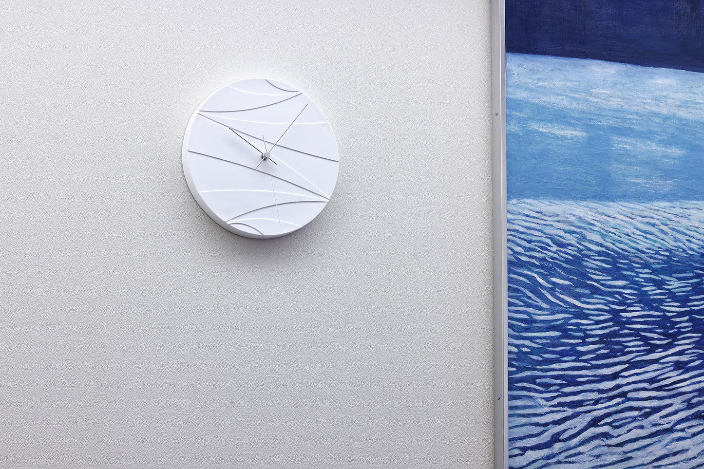 Weiße Wanduhr an der Wand mit abstrakten Linien und schlanken Zeigern