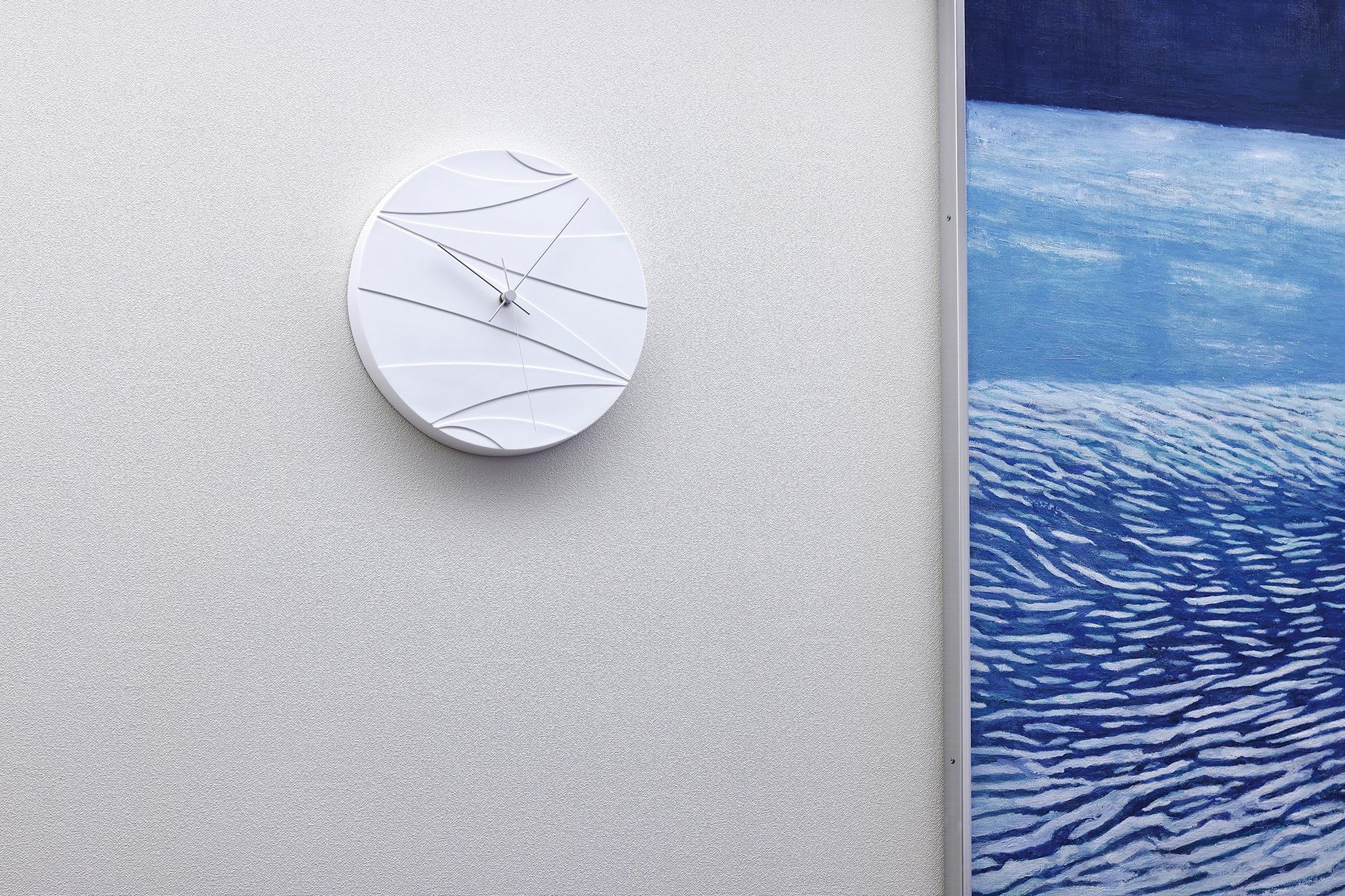 Weiße Wanduhr an der Wand mit abstrakten Linien und schlanken Zeigern