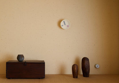 Kleine gelbe runde Wanduhr an der Wand mit minimalistischen Zeigern