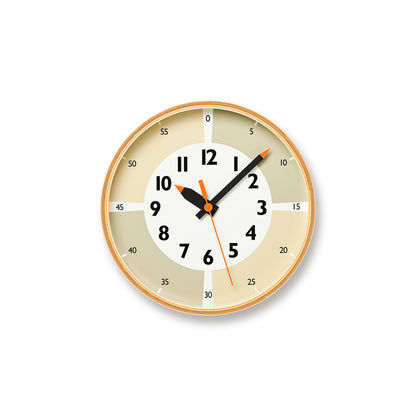Beige runde Wanduhr mit arabischen Ziffern, schwarzen Zeigern und orangefarbenem Sekundenzeiger.