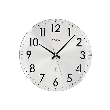 Silberne Wanduhr mit weißem Zifferblatt, schwarzen Zeigern, arabischen Zahlen und AMS-Markierung