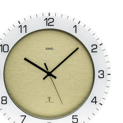 Beige Wanduhr mit weißem Rahmen, schwarzen Zeigern und runden Minutenmarkierungen