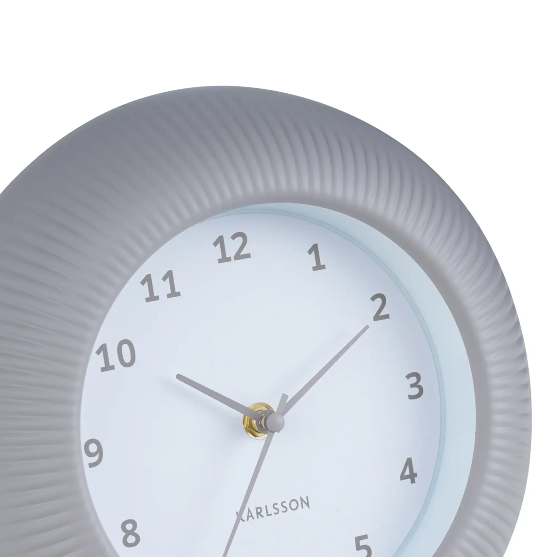 Warmgraue Wanduhr Nahansicht: geriffeltes Gehäuse, Ziffern und goldene Zeiger