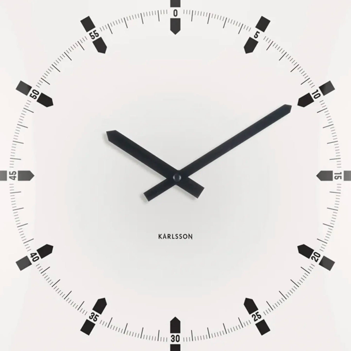 Nahaufnahme der quadratischen Wanduhr: weißes Zifferblatt, schwarze Zeiger und Minutenmarken.