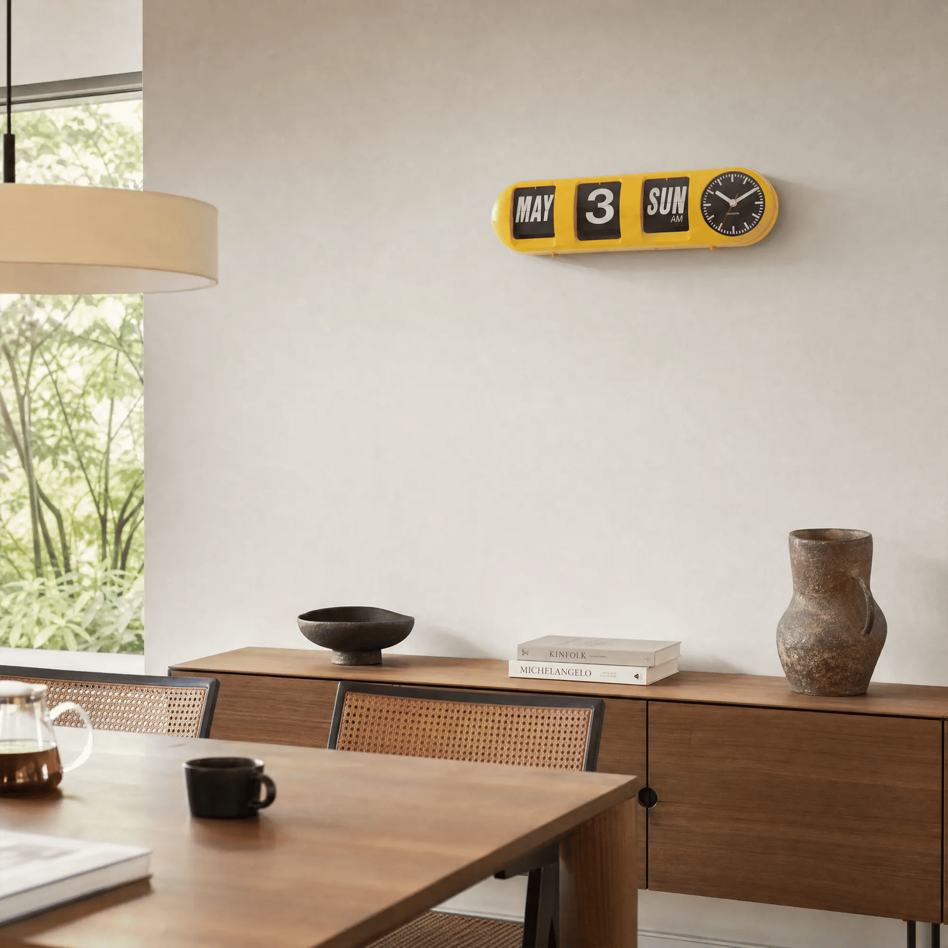 Leuchtgelbe Tube-Flip-Wanduhr an der Wand mit Klappzahlen und rundem Uhrwerk