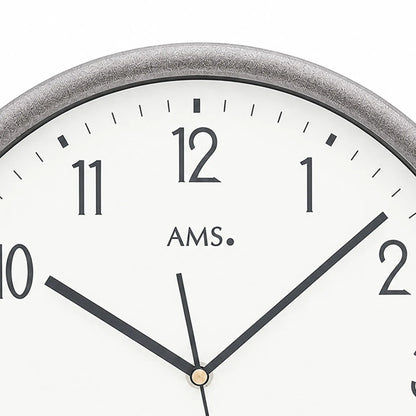 Funk-Wanduhr Nahansicht: weißes Zifferblatt mit AMS-Logo, schwarzen Zeigern und goldener Achse