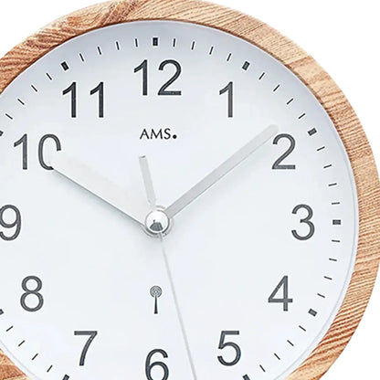 Nahaufnahme: Wanduhr mit Holzoptik-Rand, weißem Zifferblatt, AMS-Logo und Zeigern