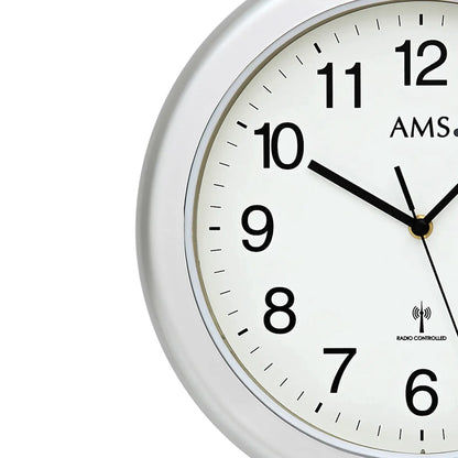Nahansicht einer runden Wanduhr: silberner Rand, weißes Ziffernblatt, schwarze Zeiger, AMS
