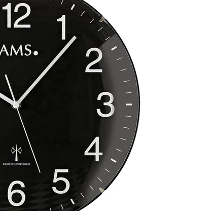 Nahaufnahme: schwarze AMS Funk-Wanduhr mit weißen Ziffern und silbernem Stundenzeiger