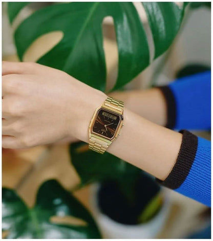 Reloj retro en la muñeca con correa de metal dorada y esfera oscura