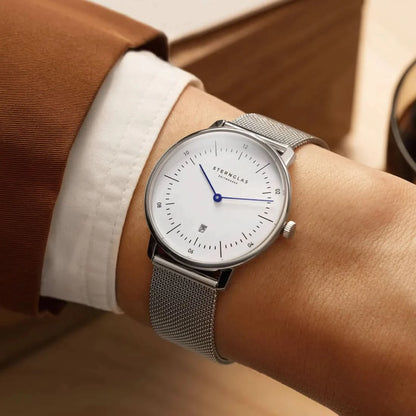 "Reloj de mujer en la muñeca, esfera blanca con manecilla azul, correa de malla"