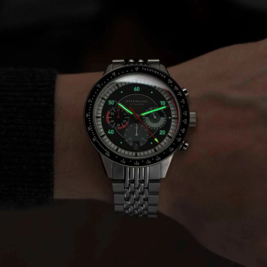 Reloj de hombre con correa de metal, esfera oscura y detalles verdes