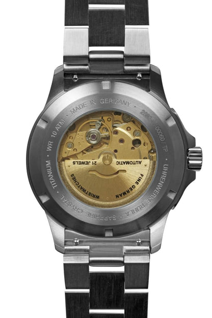 Vista trasera del reloj para hombre con la caja abierta y el movimiento visible en la correa de titanio
