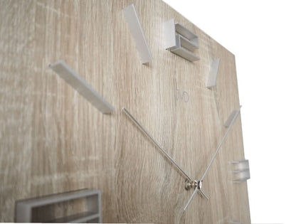 "Reloj de pared JVD en detalle: manecillas plateadas, detalles rectangulares en madera clara"
