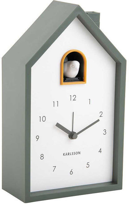 Reloj de cuco con forma de casa, carcasa gris verdosa, esfera con números del 1 al 12 y ventana naranja