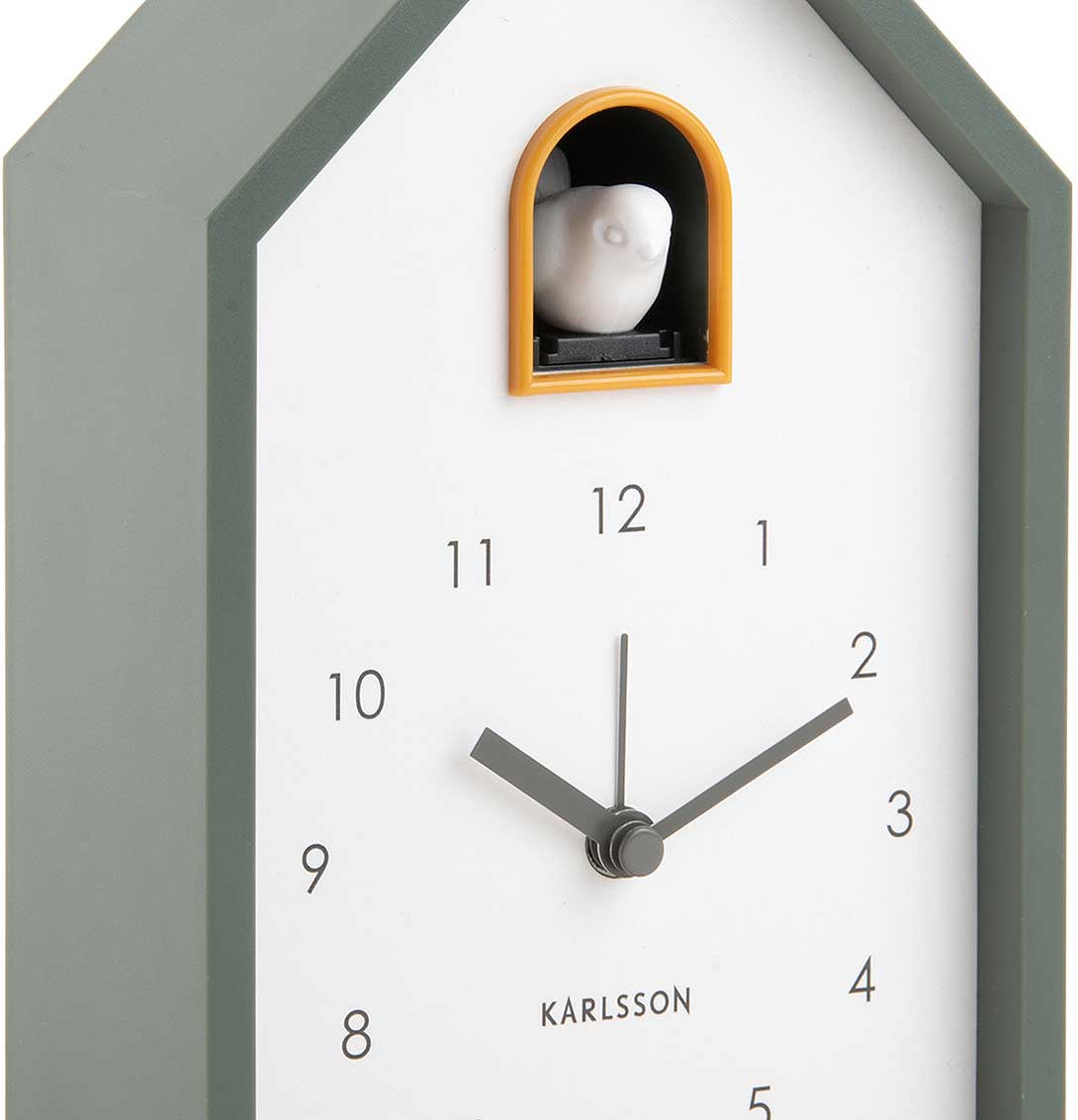 Despertador de cuco frontal: carcasa gris verdosa, esfera blanca, ventana de visualización naranja, manecillas