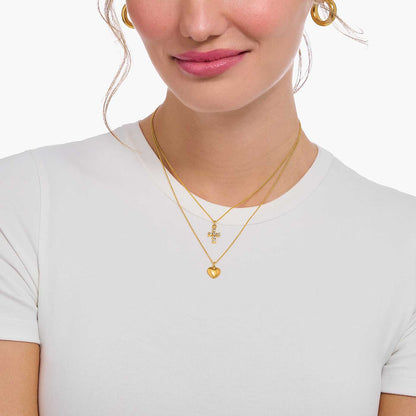 "Collar dorado en el cuello con colgante de corazón y pequeño detalle de joyería"