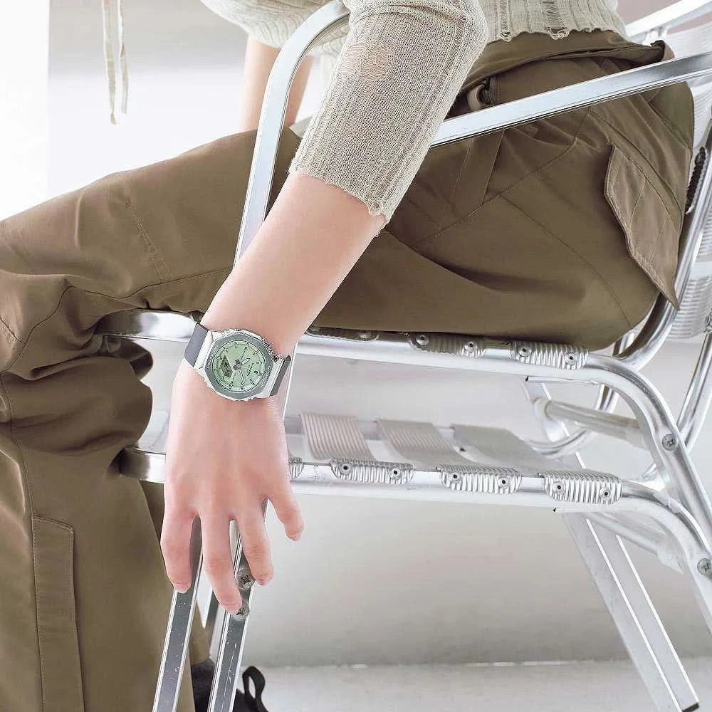 "Reloj de mujer en la muñeca: esfera verde, correa negra, caja metálica"