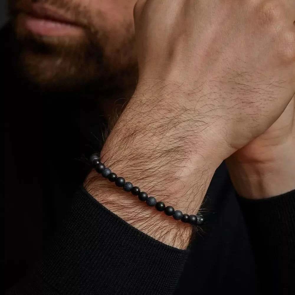 Pulsera de cuentas negras en la muñeca, con cierre negro