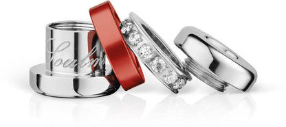 Charm de acero inoxidable en detalle: anillos plateados, cinta roja y adornos de circonita