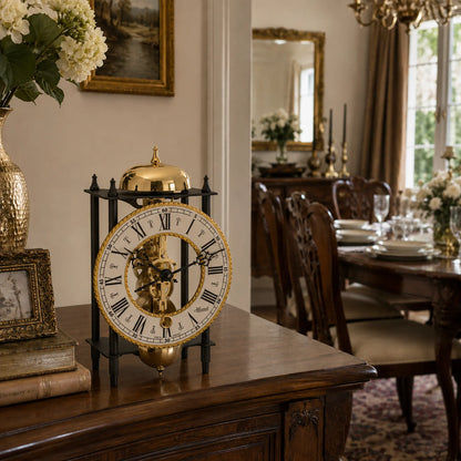 Reloj de mesa mecánico con cúpula dorada, base negra y esfera abierta