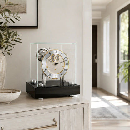 Reloj de mesa con marco de cristal, base negra y esfera beige con números romanos