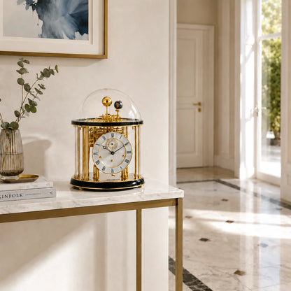 Reloj de mesa con cúpula de cristal y marco dorado, esfera blanca, base negra