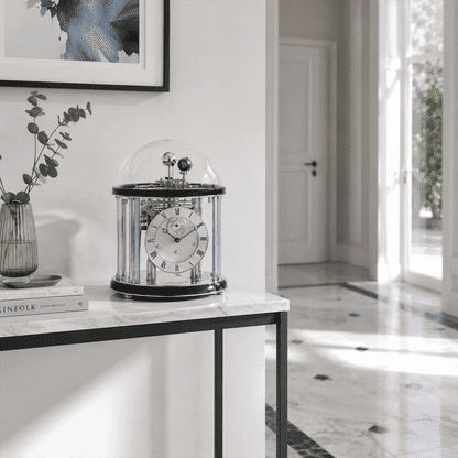 Reloj de mesa con campana de cristal y esfera blanca sobre base de piedra clara